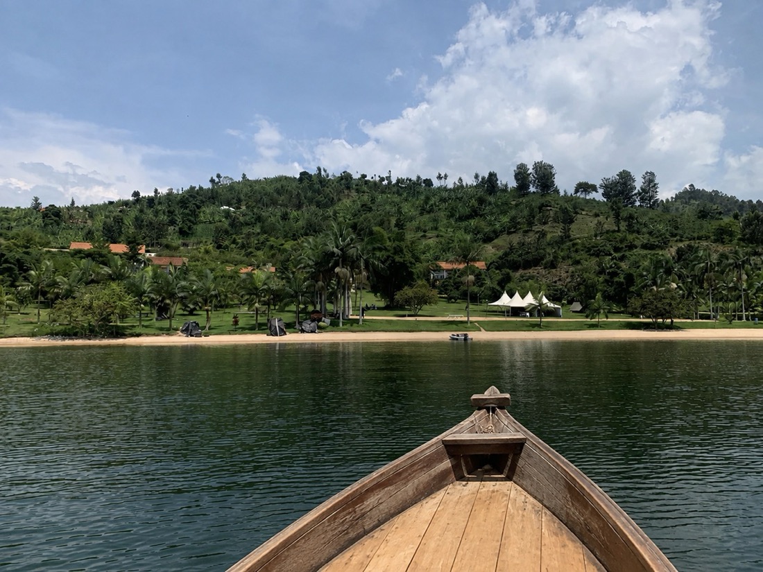 A boat on Lake Kivu with green hills and a lakeside resort, western Rwanda
